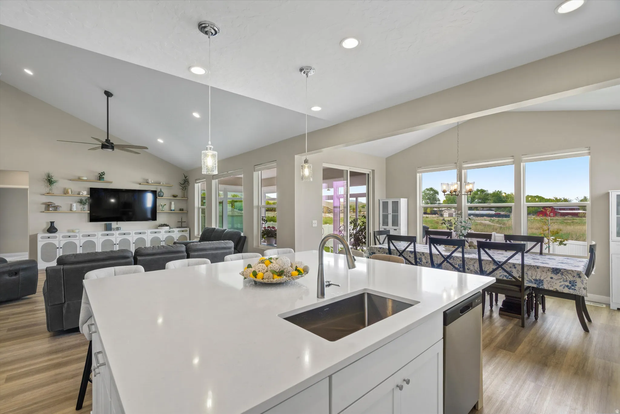 Kitchen featuring lofted ceiling, white cabinetry, dark wood-style floors, a center island with sink, and open floor plan