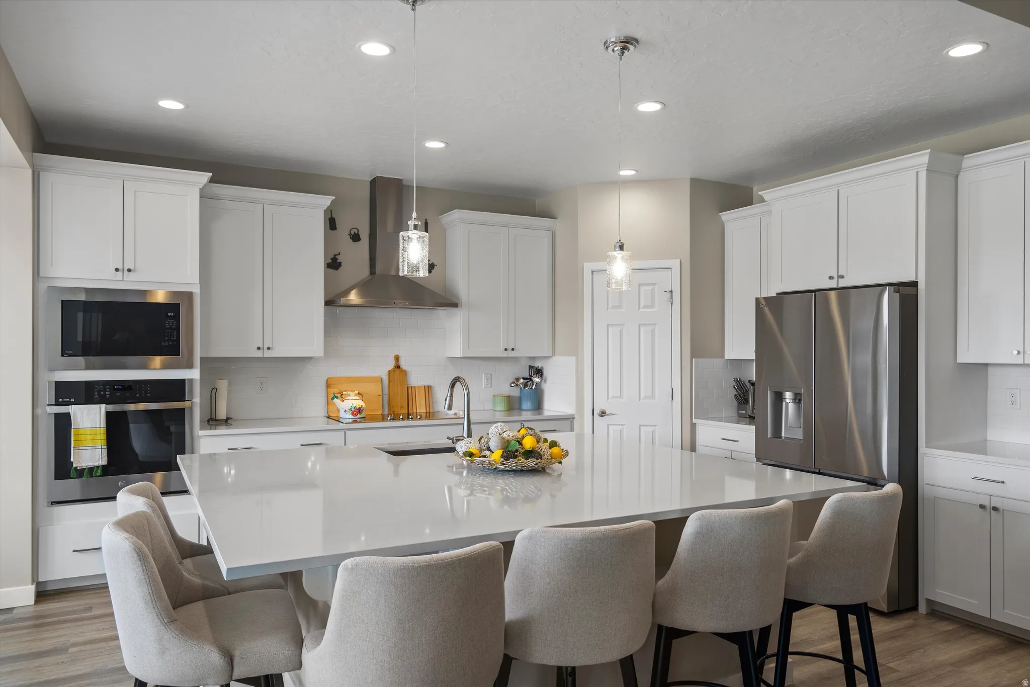 Kitchen featuring stainless steel appliances, light wood-style flooring, white cabinets, and tasteful backsplash