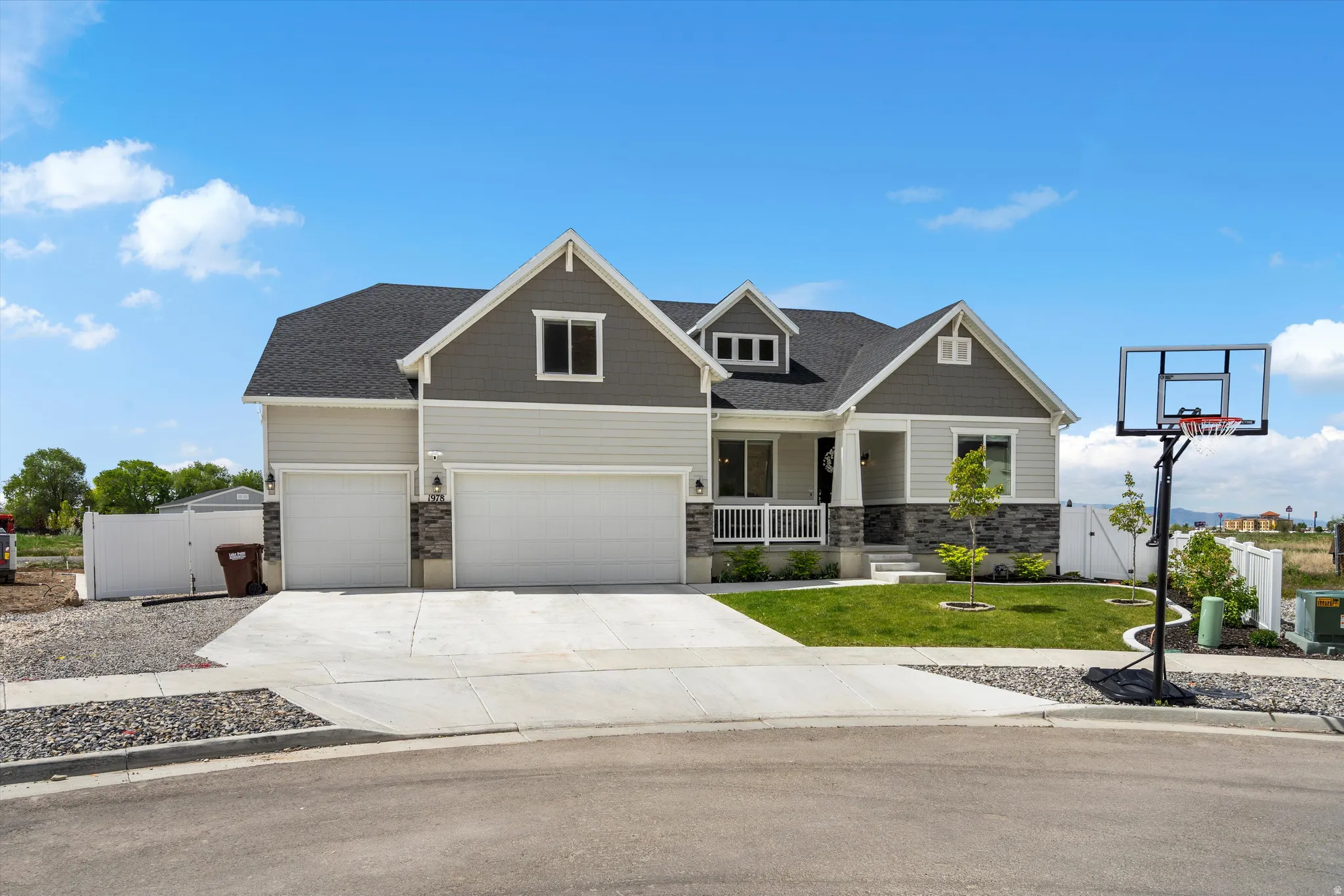 Craftsman-style house with a gate, a porch, stone siding, concrete driveway, and a shingled roof