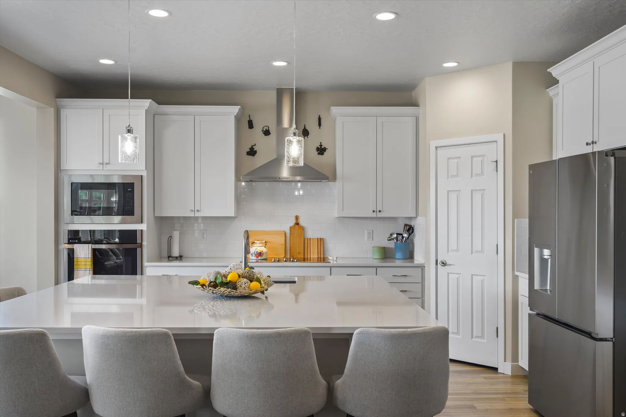 Kitchen with stainless steel appliances, white cabinets, tasteful backsplash, a kitchen island with sink, and a kitchen breakfast bar