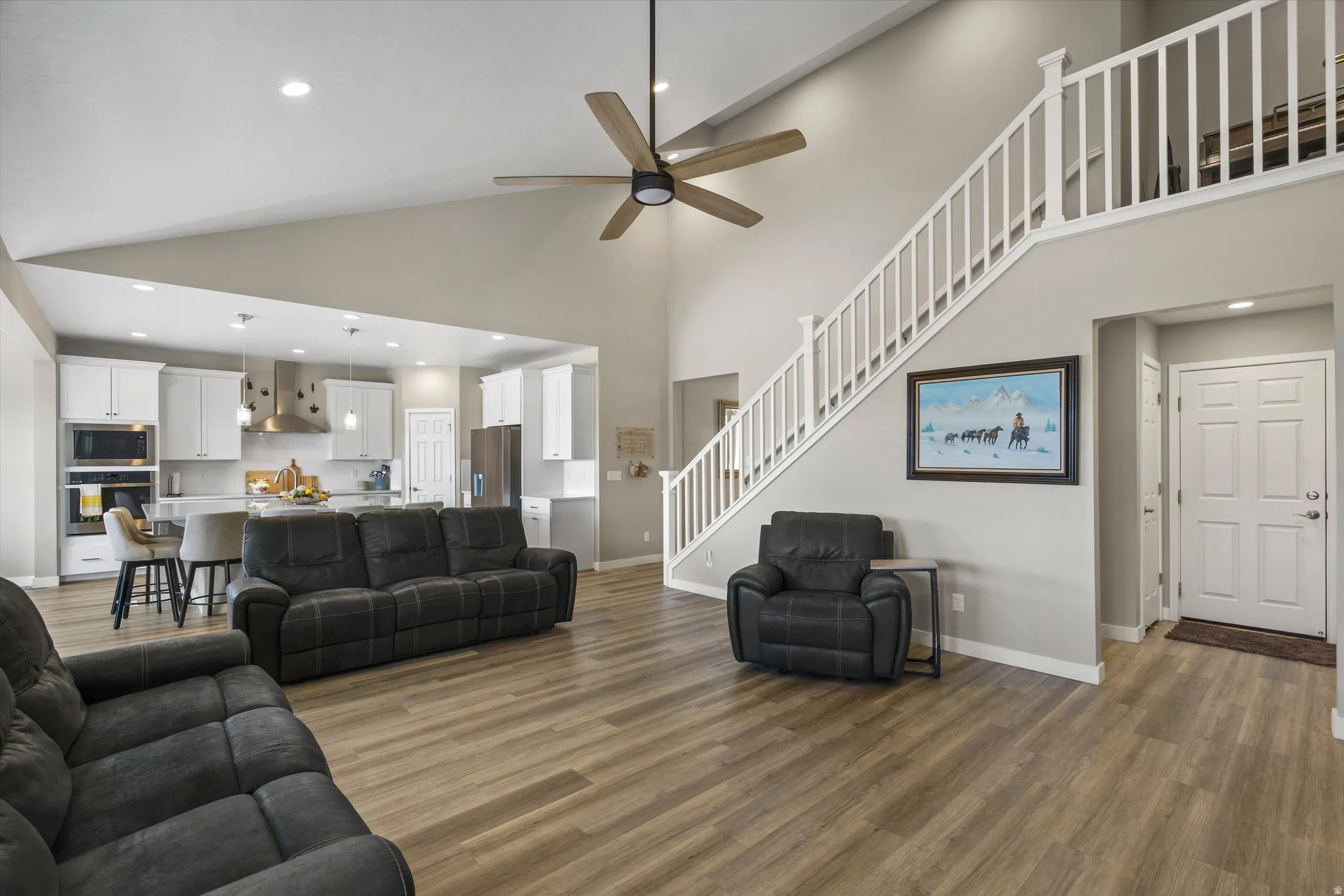 Living area with recessed lighting, dark wood-style floors, ceiling fan, and a high ceiling