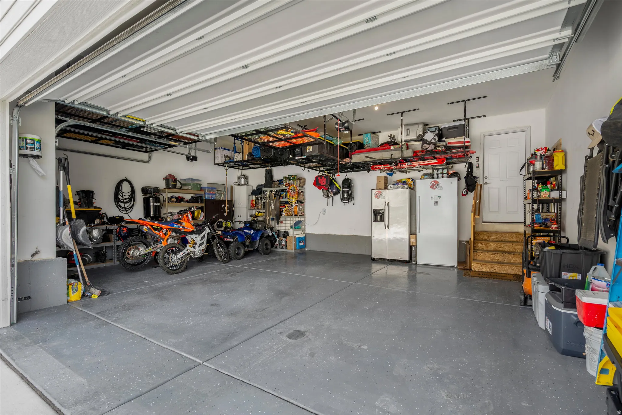 Garage with stainless steel refrigerator with ice dispenser and freestanding refrigerator