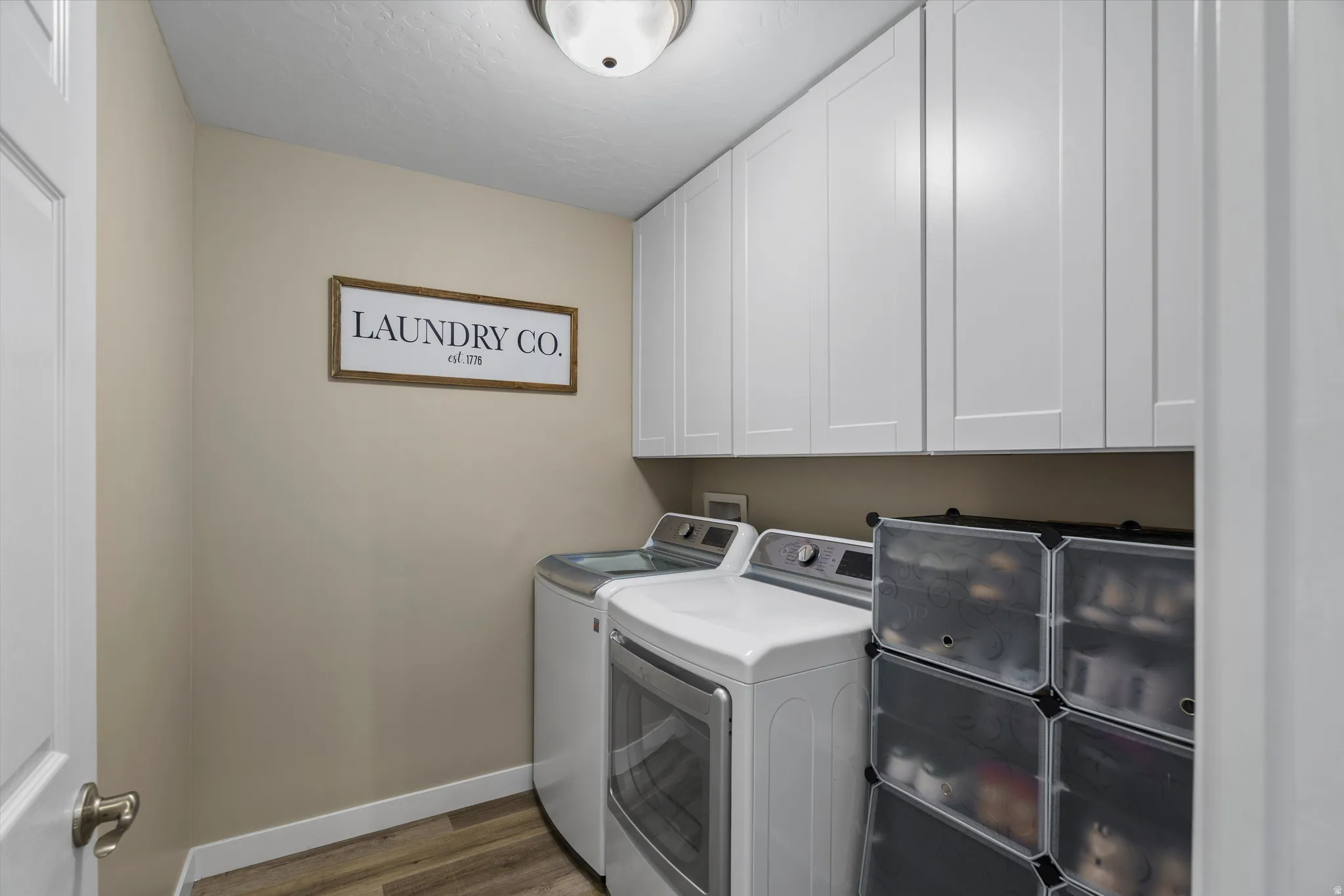 Laundry room with dark wood-style flooring, separate washer and dryer, and cabinet space