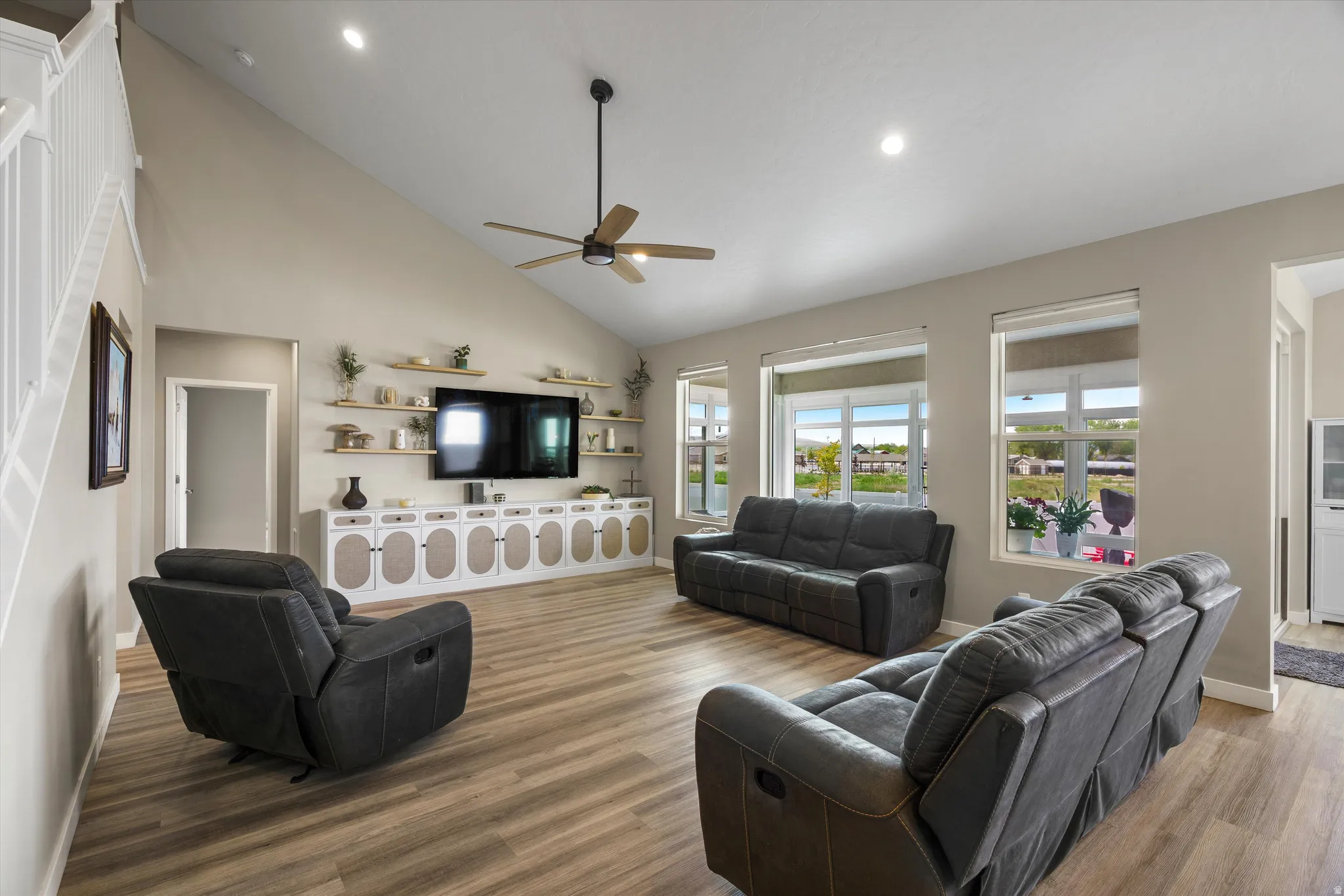 Living room with lofted ceiling, a ceiling fan, wood finished floors, and recessed lighting