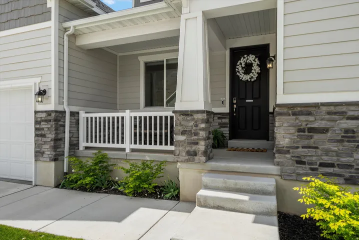 Property entrance with stone siding, a garage, and covered porch