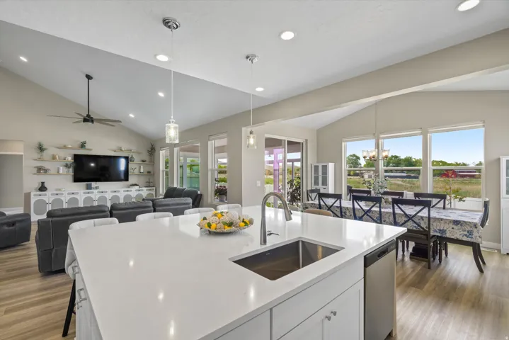 Kitchen featuring lofted ceiling, white cabinetry, dark wood-style floors, a center island with sink, and open floor plan
