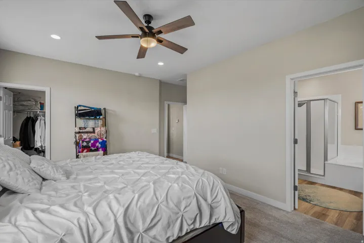 Bedroom featuring recessed lighting, a ceiling fan, a walk in closet, and light colored carpet