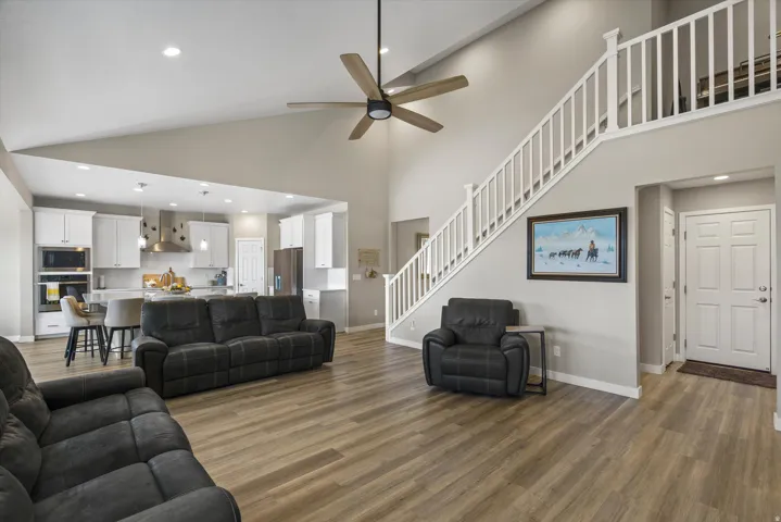 Living area with recessed lighting, dark wood-style floors, ceiling fan, and a high ceiling