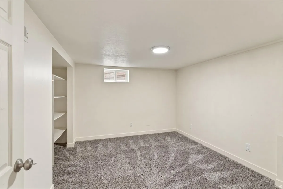 Finished below grade area featuring baseboards and dark colored carpet