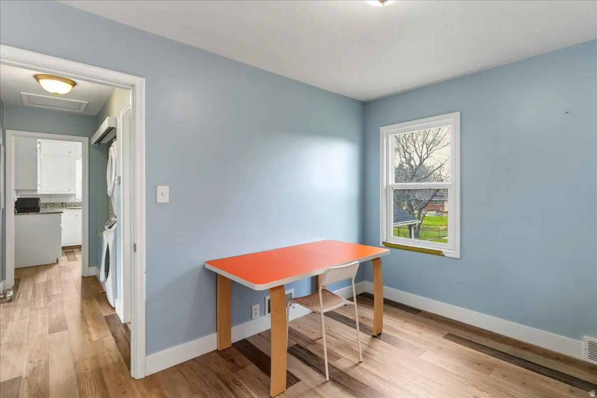 Office with stacked washer and clothes dryer and light wood finished floors