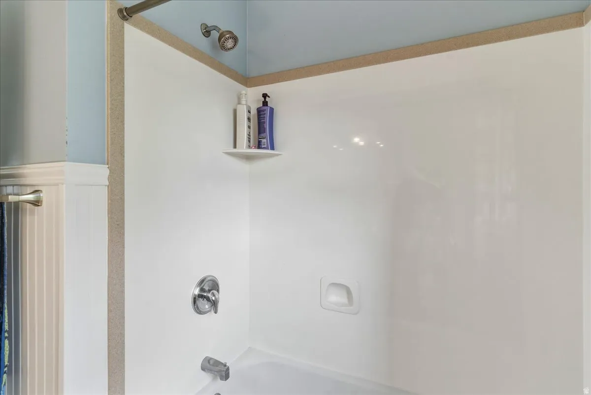 Bathroom featuring washtub / shower combination and wainscoting