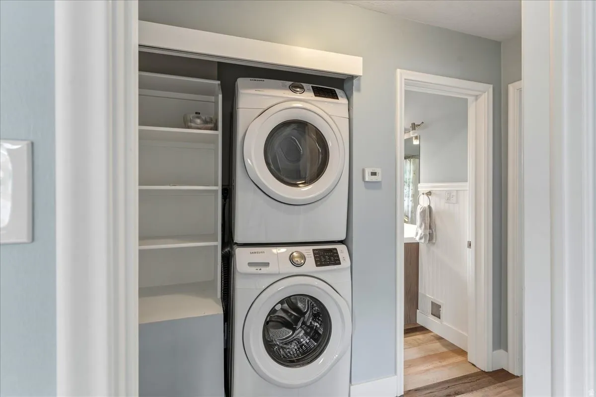 Laundry area featuring stacked washer and dryer and light wood-type flooring