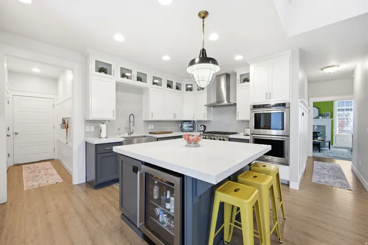 Kitchen with dual tone cabinets, glass insert cabinets, a kitchen island, light stone counters, and stainless steel appliances