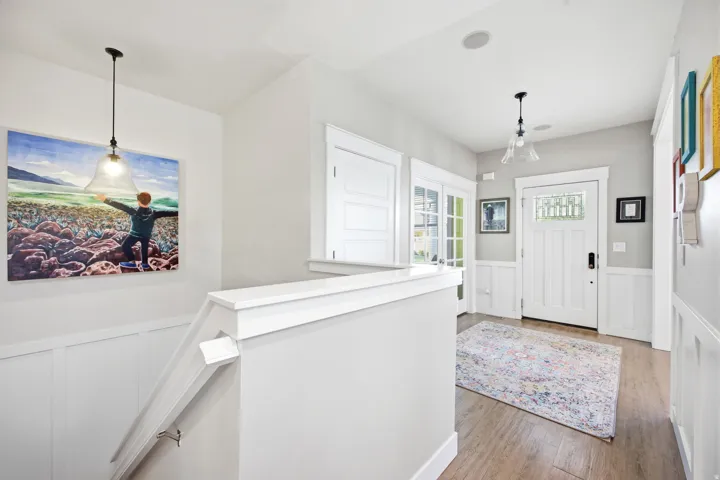 Foyer entrance featuring a wainscoted wall, a decorative wall, and light wood-style flooring