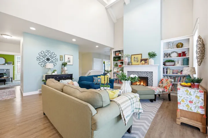 Living room featuring a tile fireplace, built in features, a high ceiling, and wood finished floors