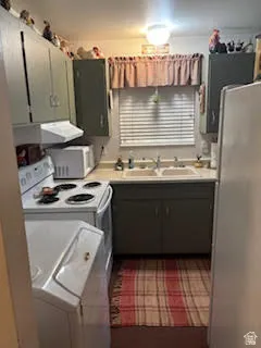 Kitchen featuring light countertops, washer / dryer, white appliances, and exhaust hood