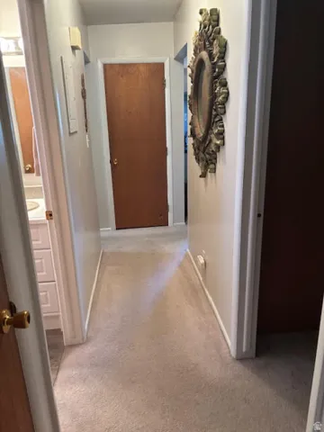 Hall featuring light carpet and baseboards