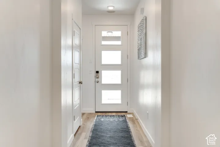 Entryway featuring a white four-panel door with opaque glass inserts and wood-finish flooring