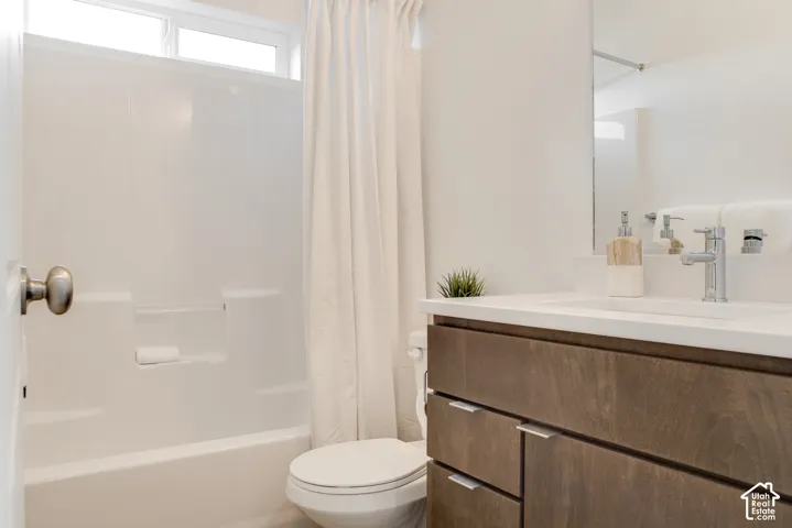 White bathtub with integrated shelving, transom window, wood-finish vanity, and integrated sink with chrome faucet