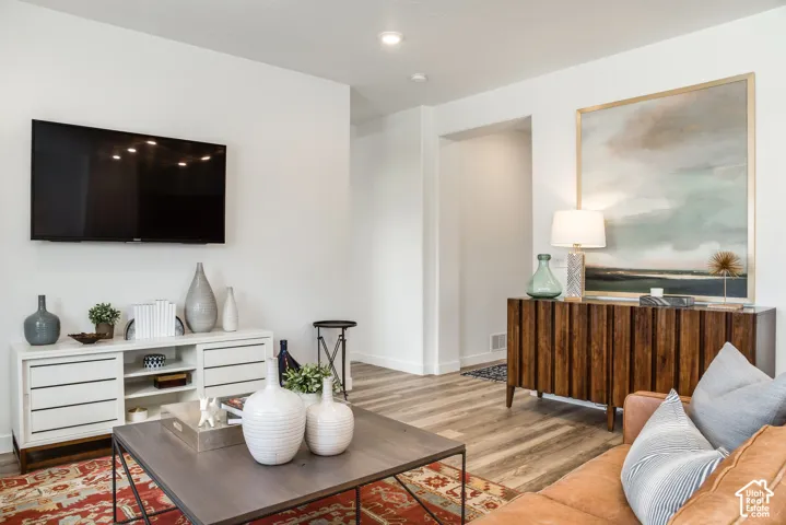 Recessed ceiling lighting, wood-finish flooring, white baseboards, and white wall finishes
