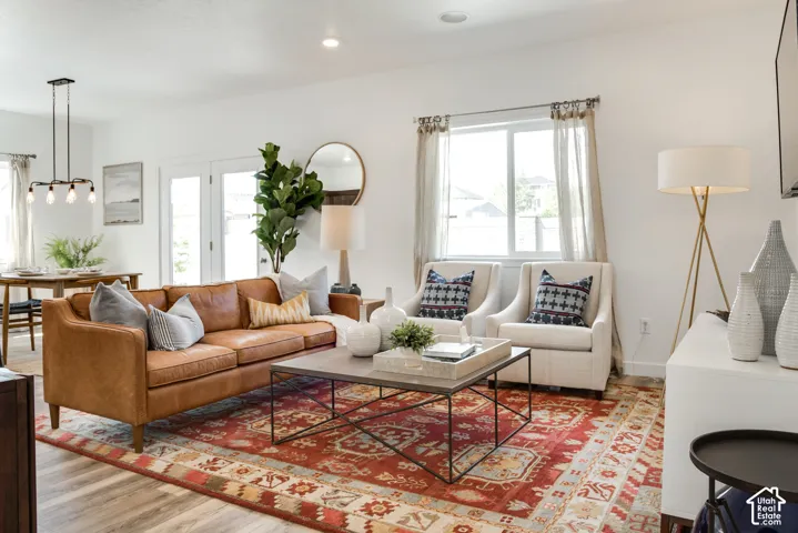 Recessed ceiling lighting, wood-finish flooring, white double French doors, and a dining area with a modern chandelier