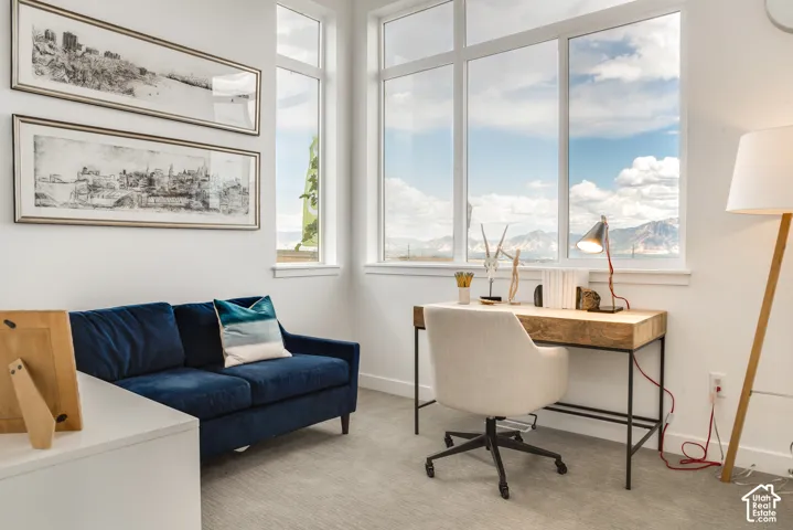 Floor-to-ceiling windows, white interior walls, and light gray carpeting