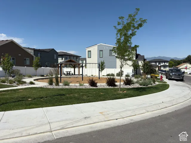 Community green space featuring a swing set, covered picnic area, and landscaped planting beds