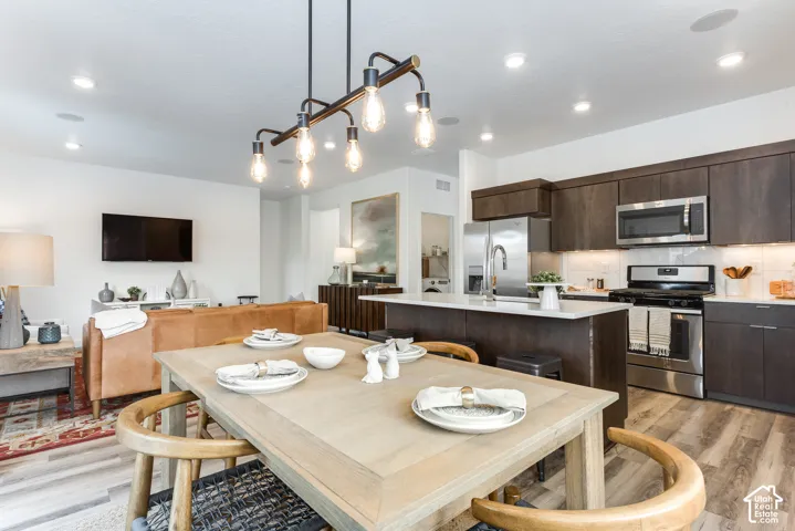 Open-concept living space featuring wood-finish flooring, recessed ceiling lights, and a modern linear chandelier