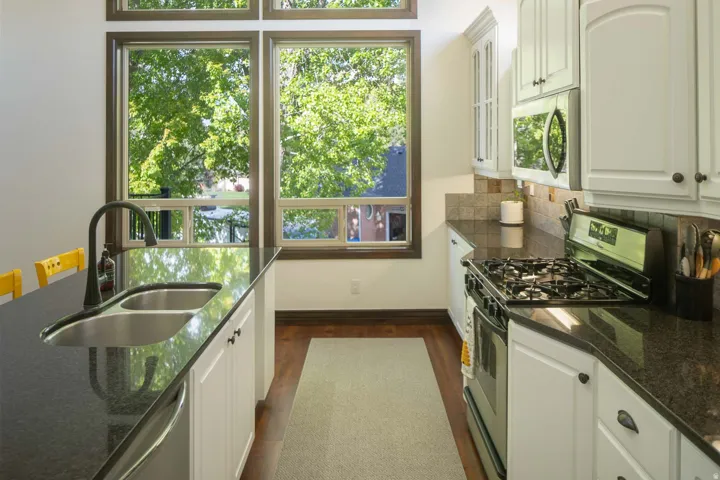 Kitchen with dark stone counters, stainless steel appliances, and white cabinets