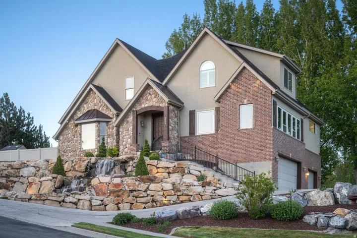 View of front facade with stucco siding, a garage, stone siding, and brick siding
