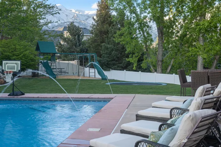 View of swimming pool featuring a mountain view, a playground, and a fenced backyard