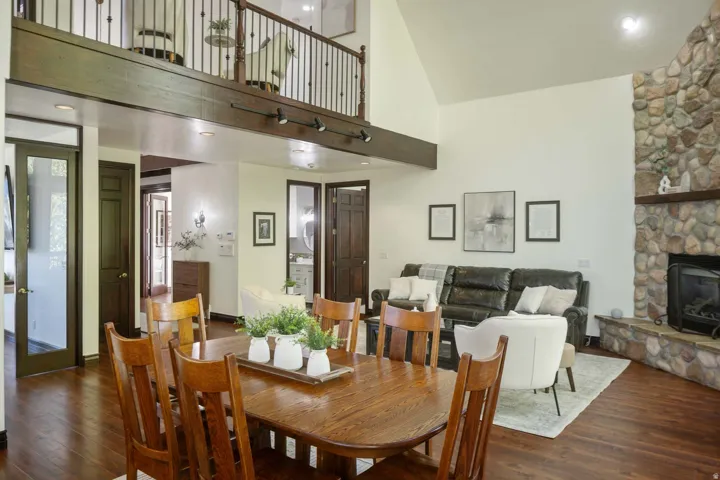 Dining room featuring dark wood-style flooring, recessed lighting, vaulted ceiling, and a fireplace