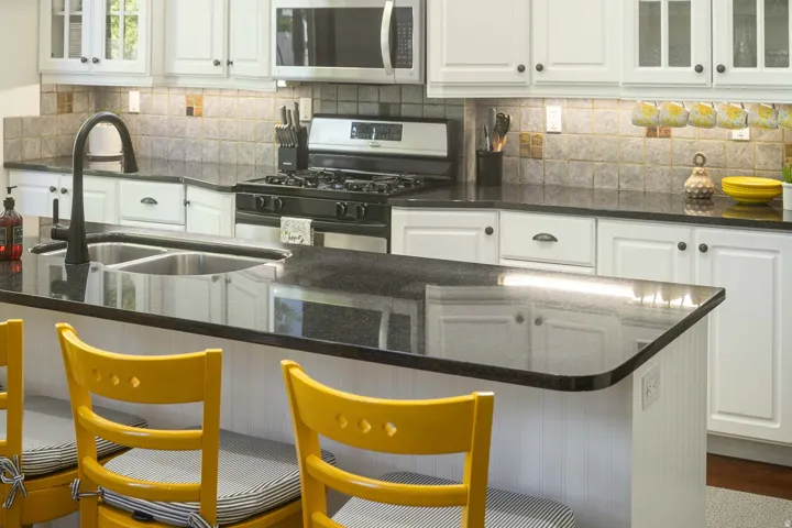 Kitchen with glass fronted cabinets, white cabinetry, and black gas range oven
