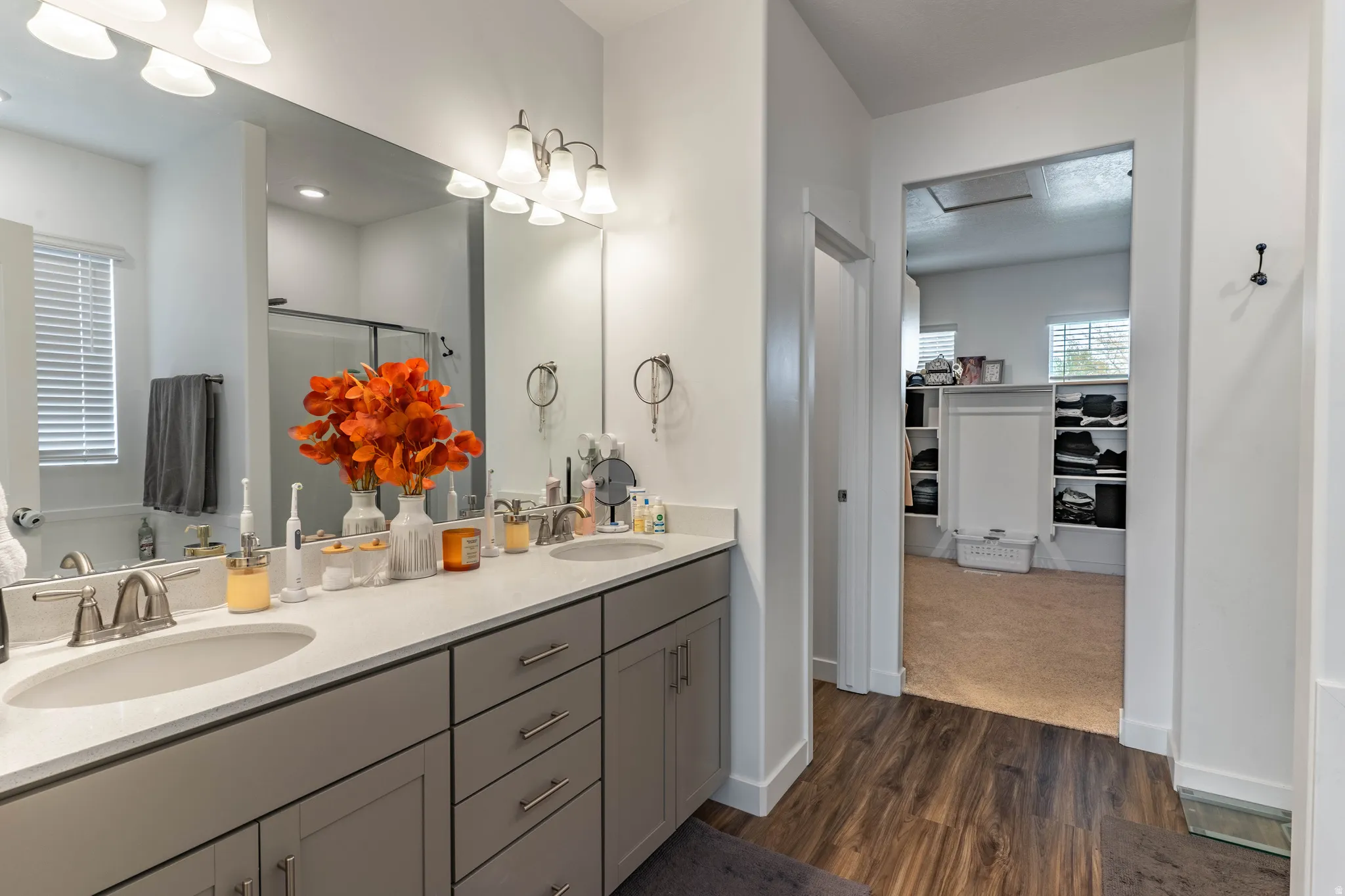 Bathroom featuring double vanity, a shower stall, dark wood-style flooring, and a walk in closet