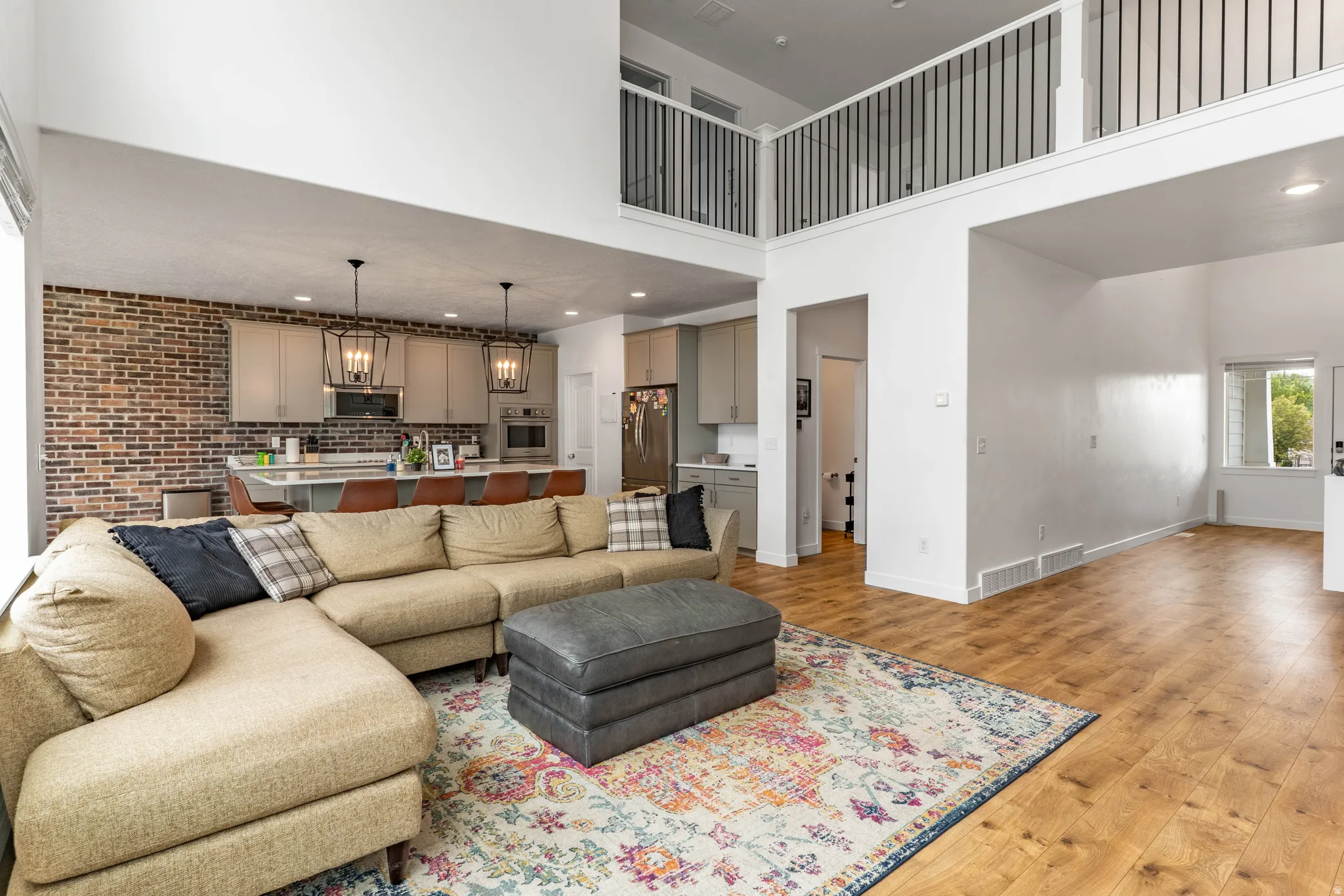 Living area with light wood-type flooring, recessed lighting, a high ceiling, and brick wall