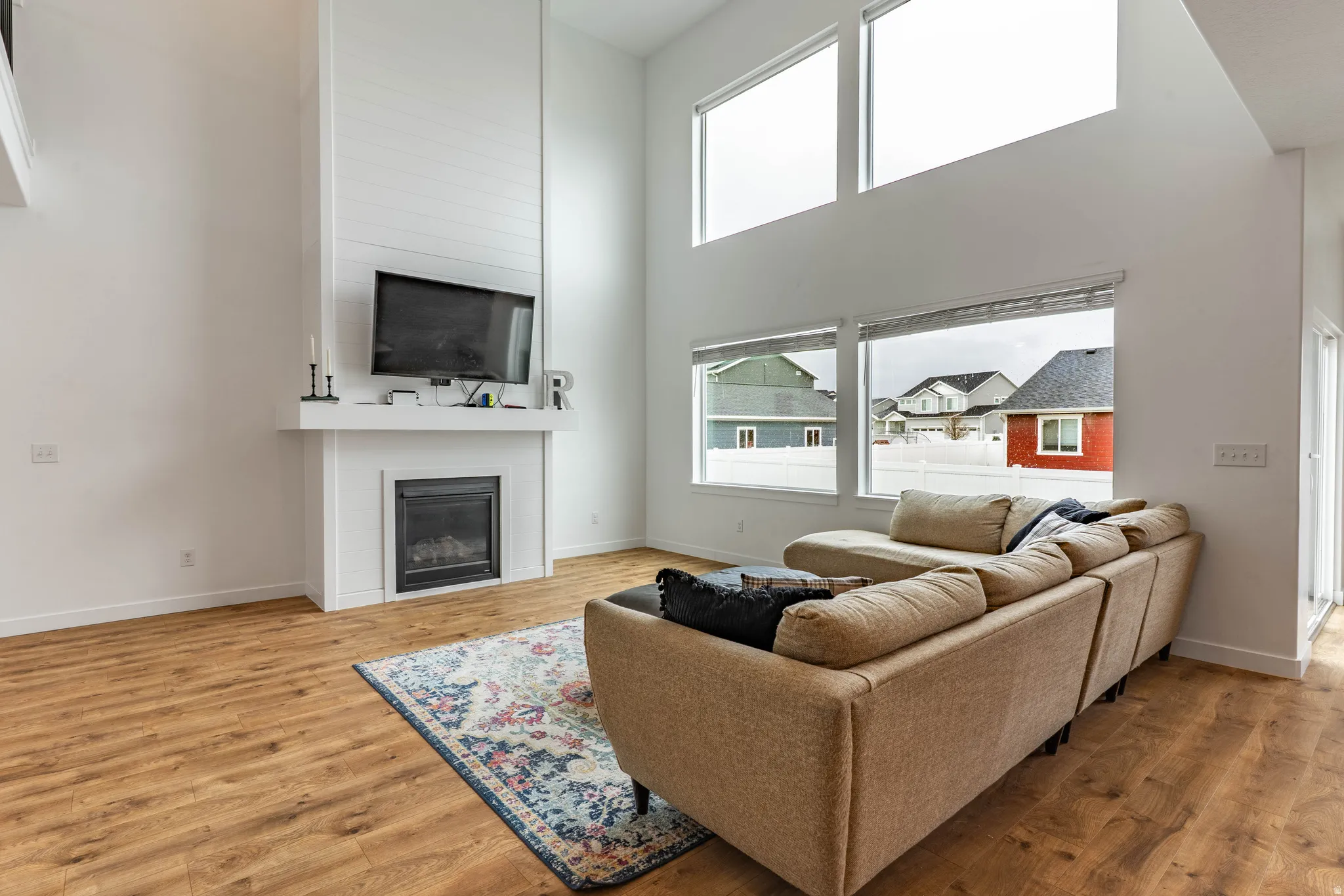 Living room featuring a high ceiling, light wood finished floors, and a fireplace