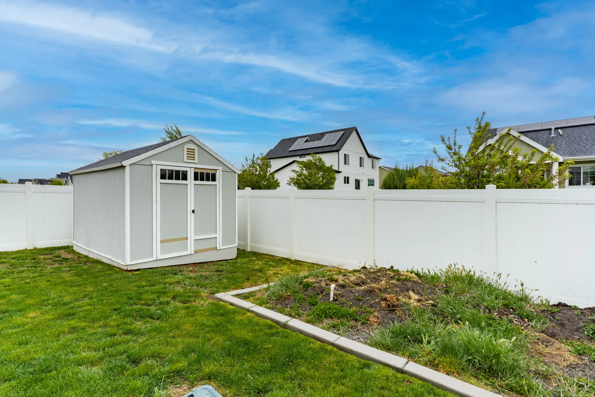 Fenced backyard featuring a shed