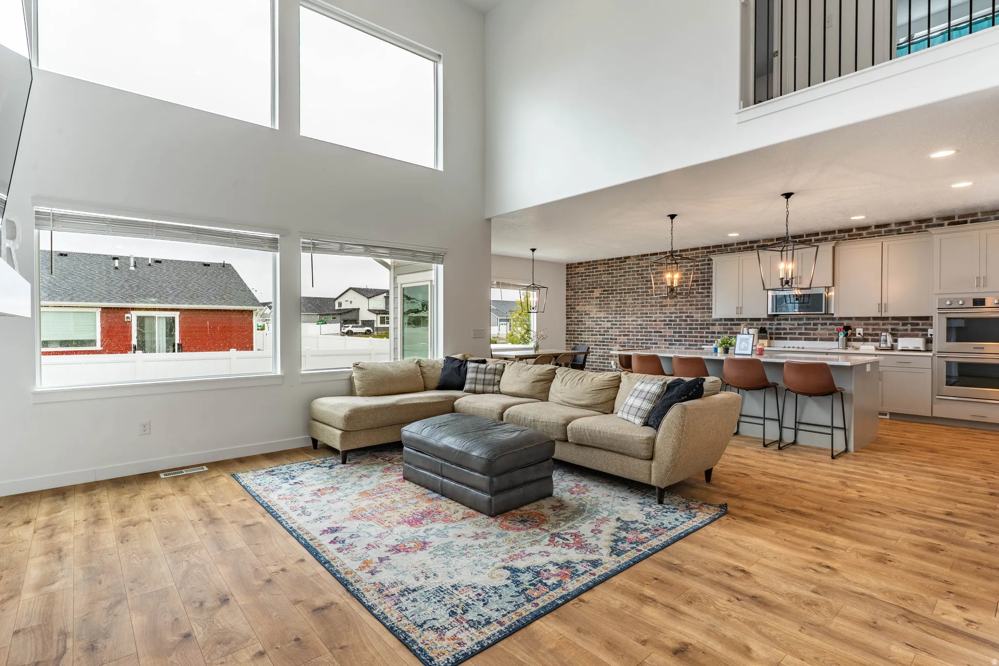 Living area featuring light wood-style flooring, a high ceiling, and recessed lighting