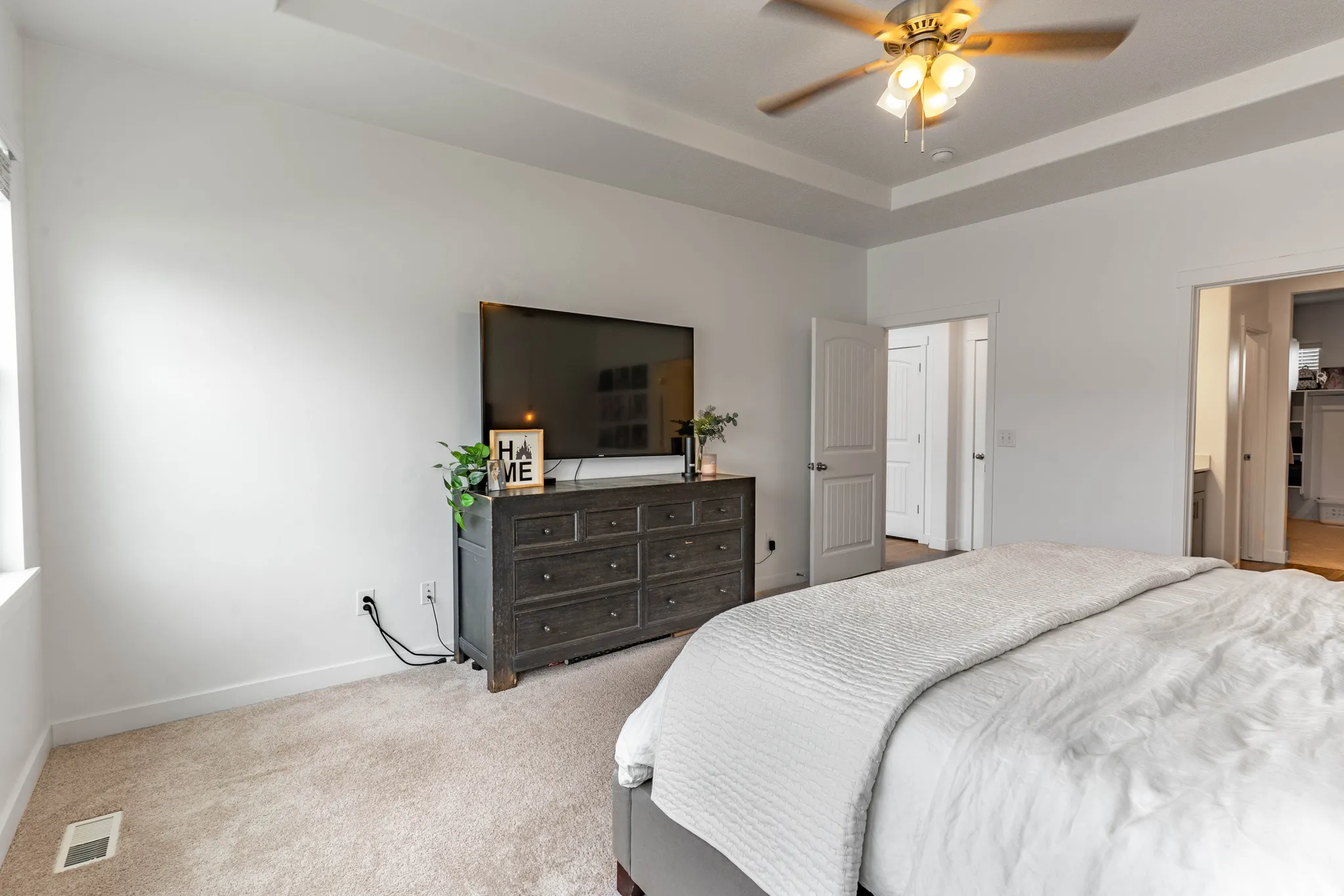Carpeted bedroom featuring a ceiling fan and a tray ceiling