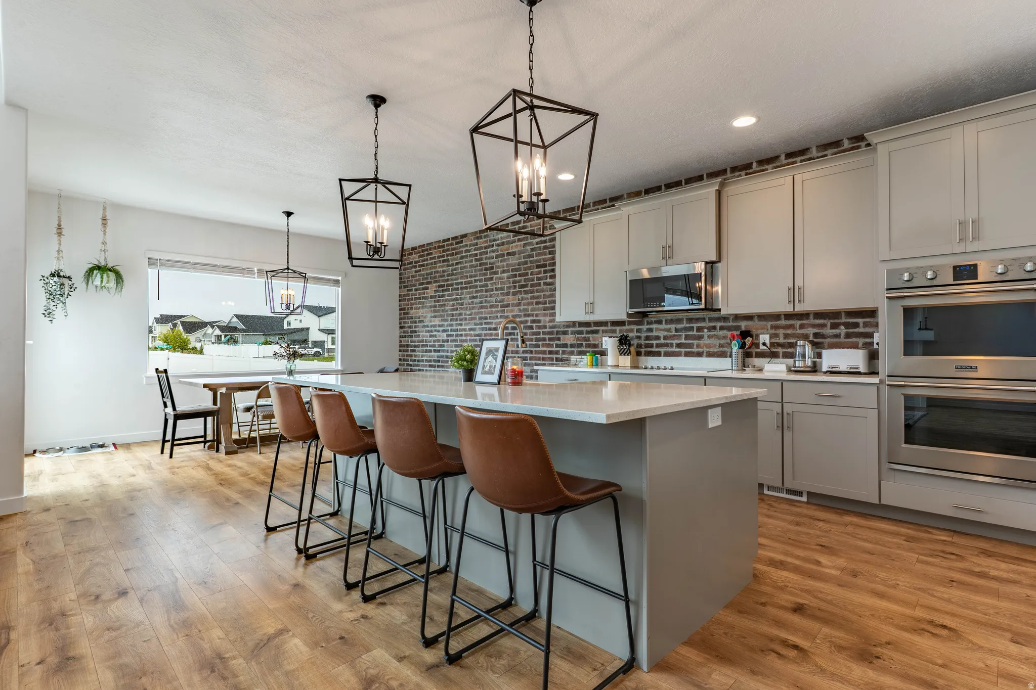 Kitchen with a kitchen island with sink, stainless steel appliances, a breakfast bar area, gray cabinetry, and light wood-type flooring