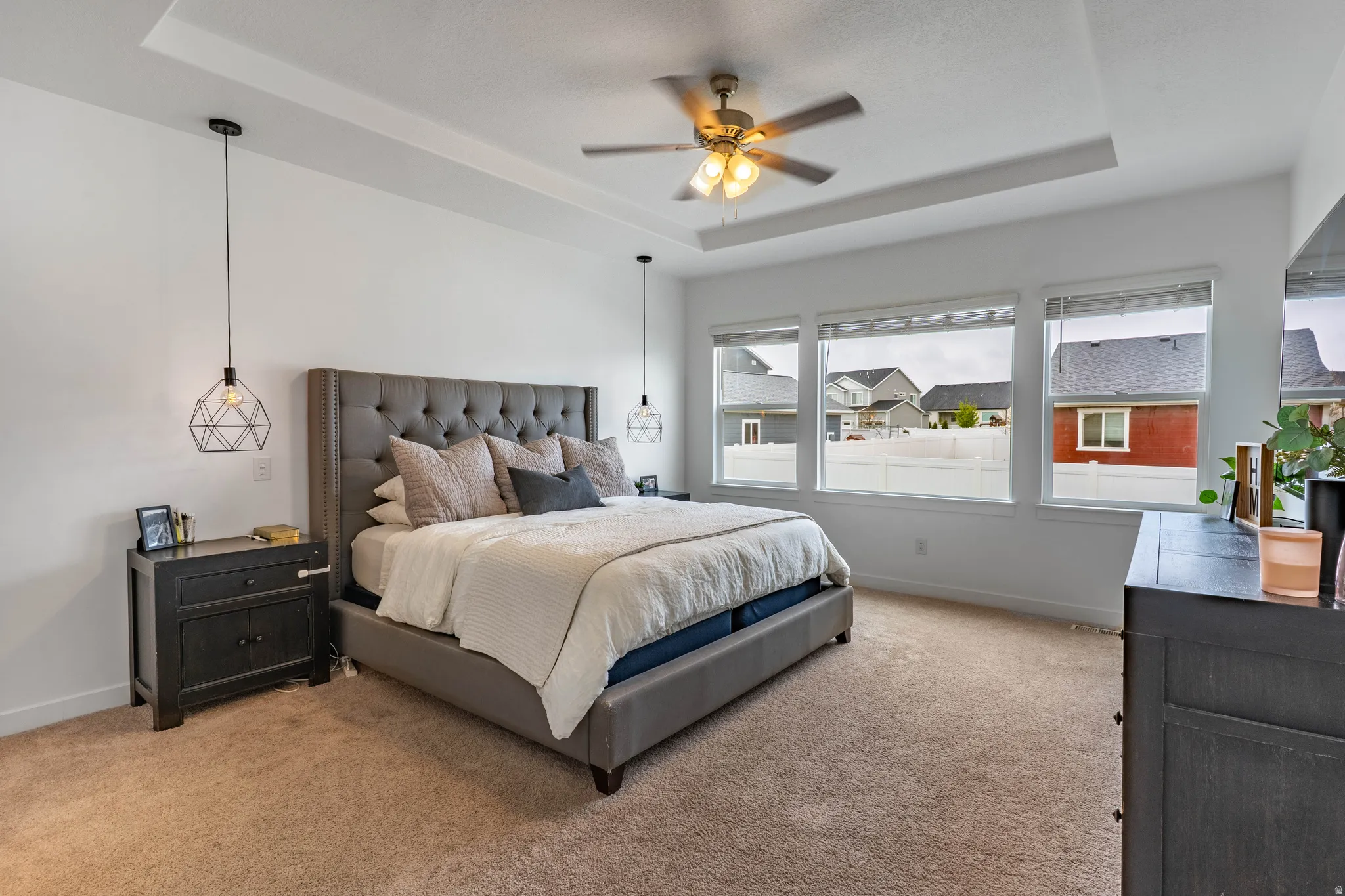 Bedroom featuring a raised ceiling, carpet floors, and a ceiling fan