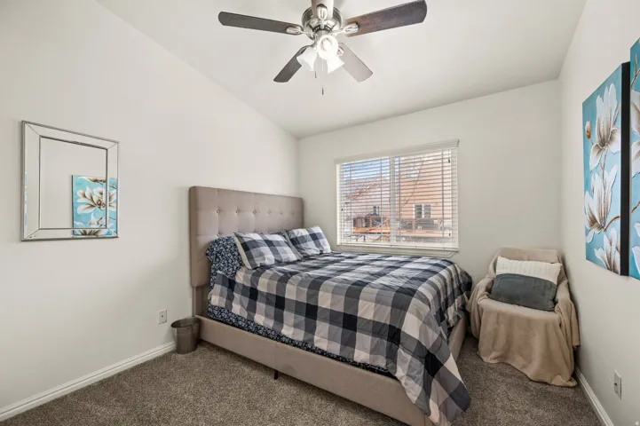 Carpeted bedroom with vaulted ceiling and ceiling fan