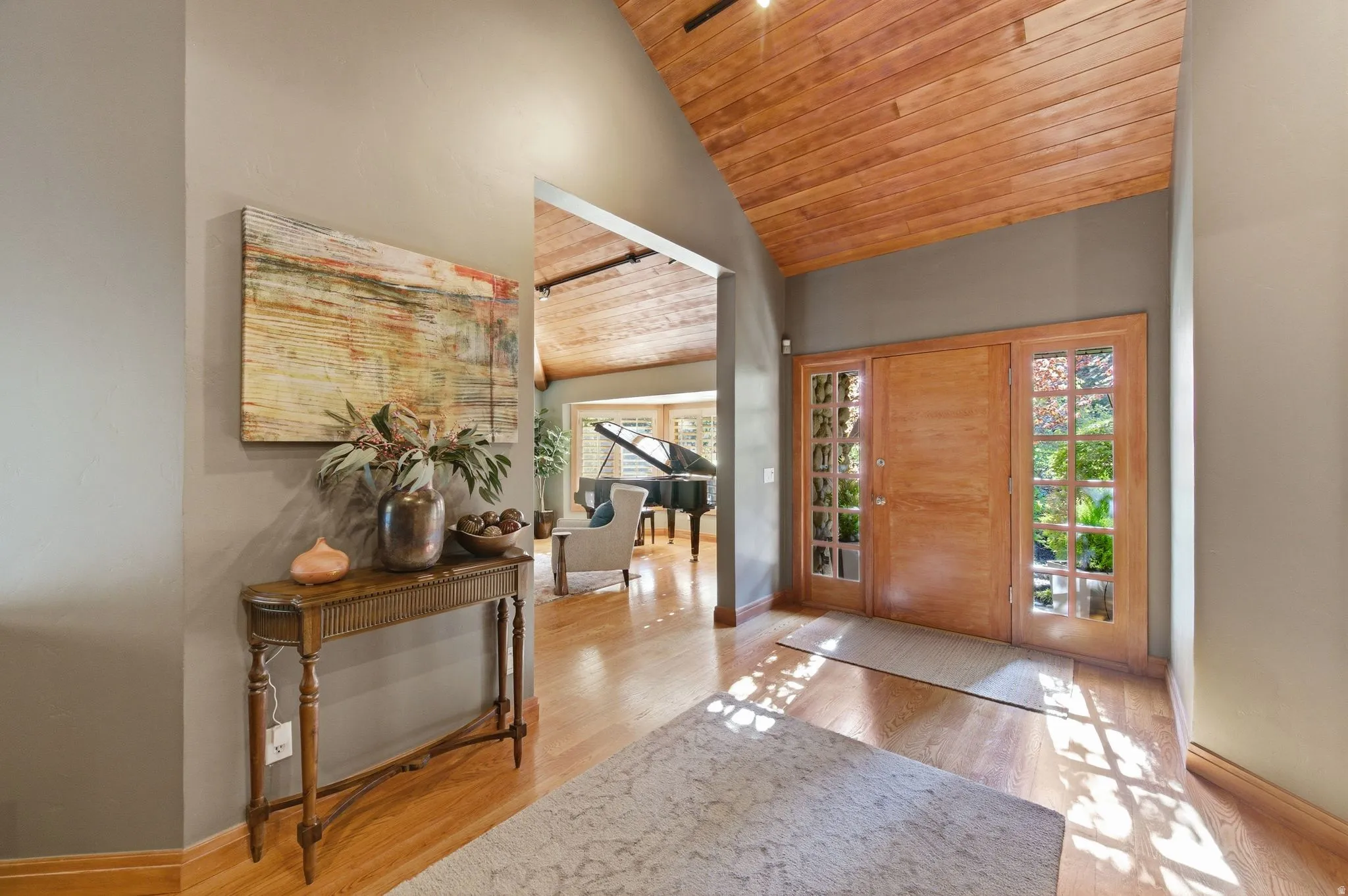 Entryway featuring a vaulted wooden ceiling, light wood-style flooring, and plenty of natural light