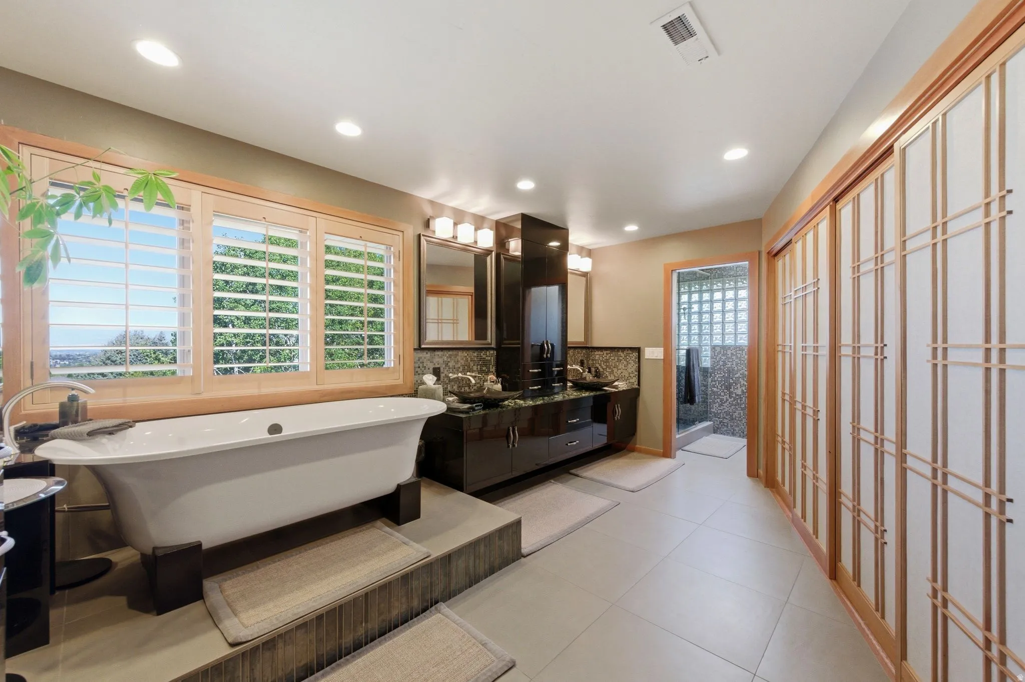 Bathroom with double vanity, a freestanding tub, recessed lighting, backsplash, and a walk in shower