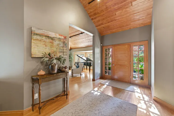 Entryway featuring a vaulted wooden ceiling, light wood-style flooring, and plenty of natural light