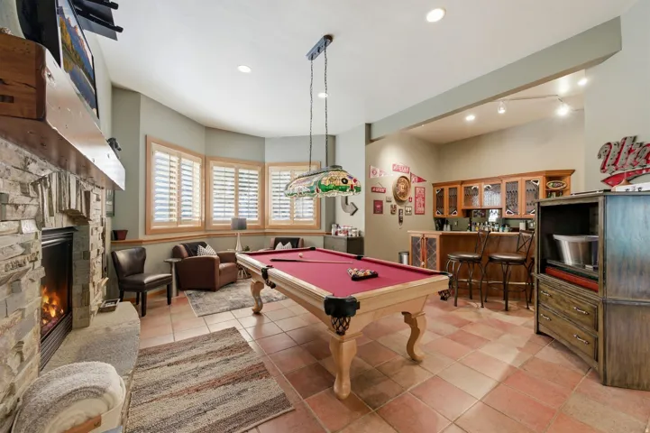 Recreation room featuring a stone fireplace, pool table, bar area, light tile patterned floors, and recessed lighting