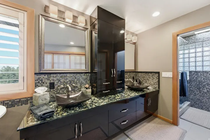 Bathroom with healthy amount of natural light, double vanity, a stall shower, and light tile patterned floors