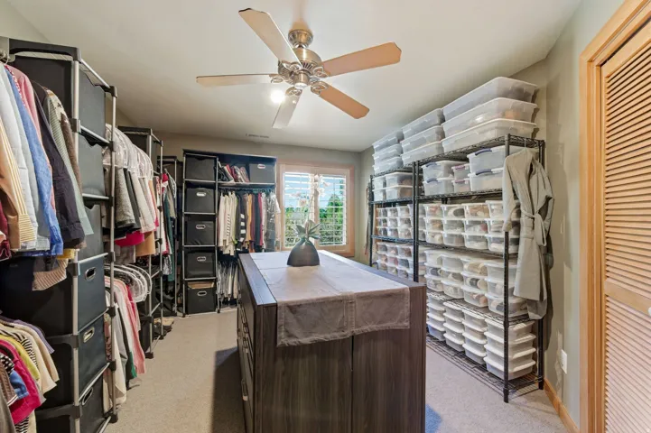 Walk in closet featuring light colored carpet and ceiling fan