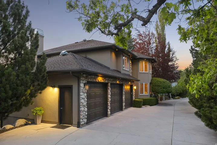 View of front facade featuring stucco siding, stone siding, driveway, and a chimney