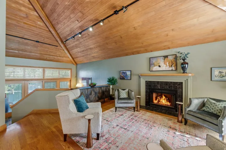 Living area featuring a vaulted wood ceiling, rail lighting, wood finished floors, and a fireplace